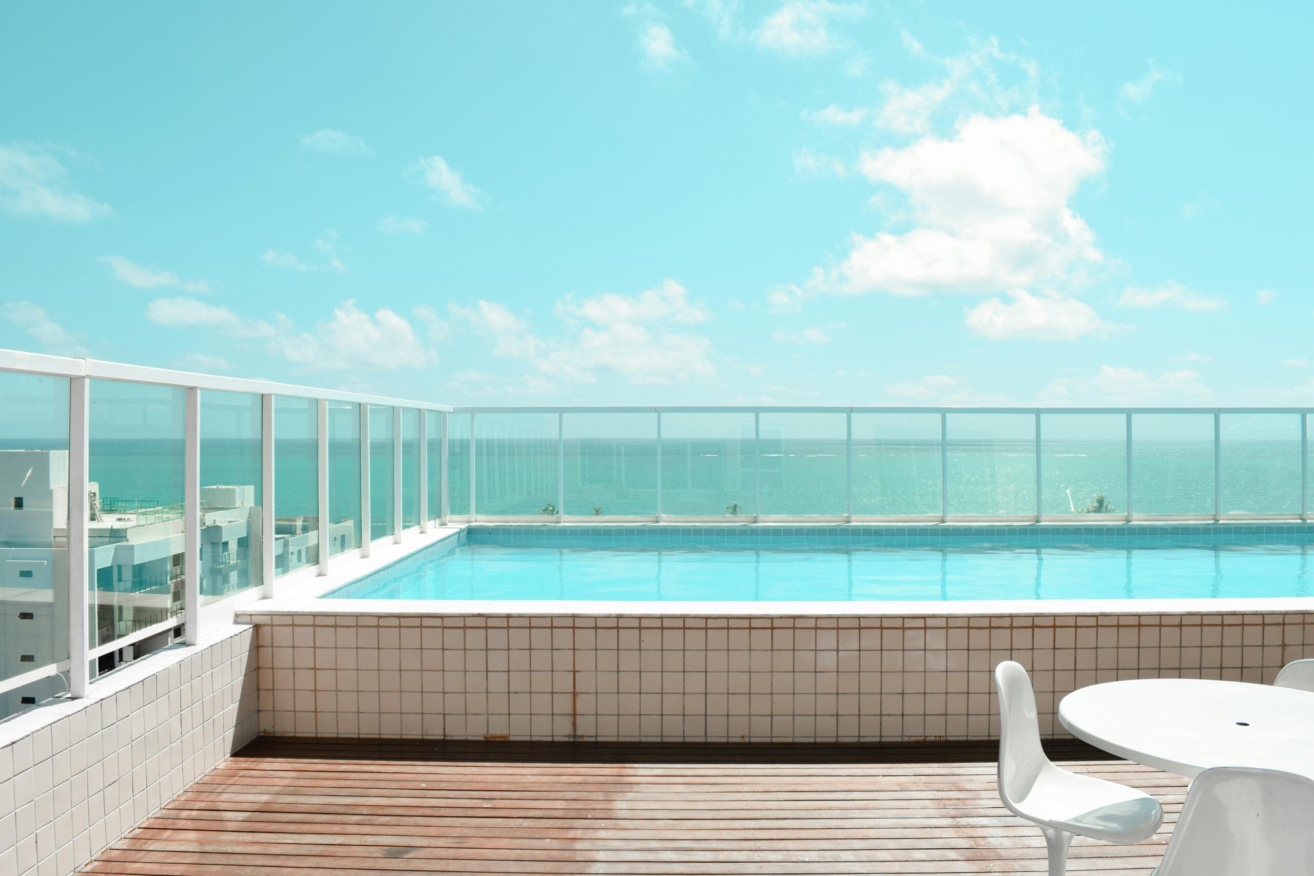 Serene rooftop infinity pool with stunning ocean view under a bright blue sky.